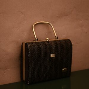 Vintage bag with golden handle placed on reflecting surface as accessory for garment