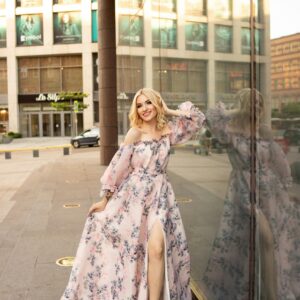 Woman in Floral High Slit Maxi Dress Leaning on Glass Facade